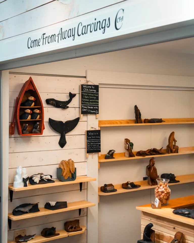 Handcrafted wood carvings on display, including seabirds and iceberg shapes, at Come From Away Carvings.