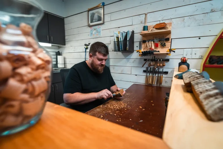 Nathan Keil hand-carving a whale tail design into wood at Come From Away Carvings.